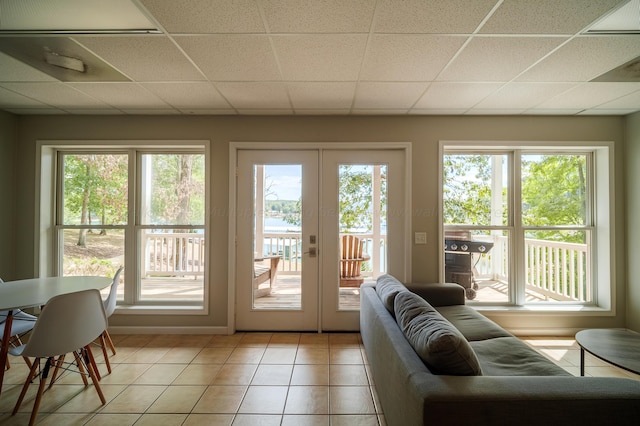 entryway featuring tile patterned floors, a wealth of natural light, a drop ceiling, and french doors