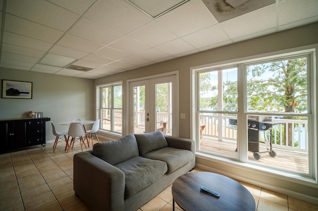 tiled living room featuring french doors and a drop ceiling