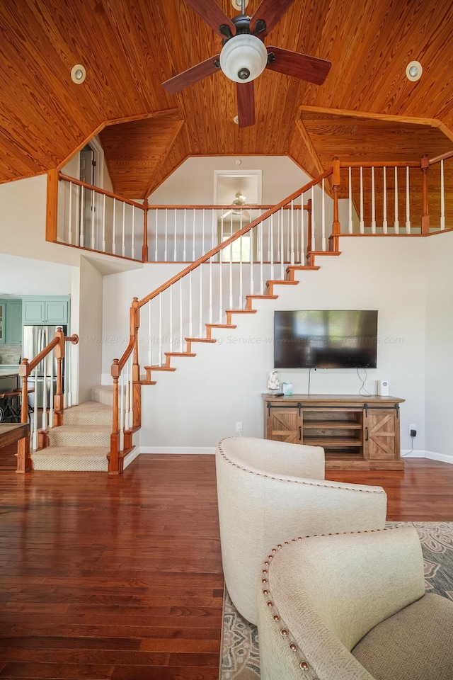 living room with hardwood / wood-style flooring, ceiling fan, a towering ceiling, and wood ceiling