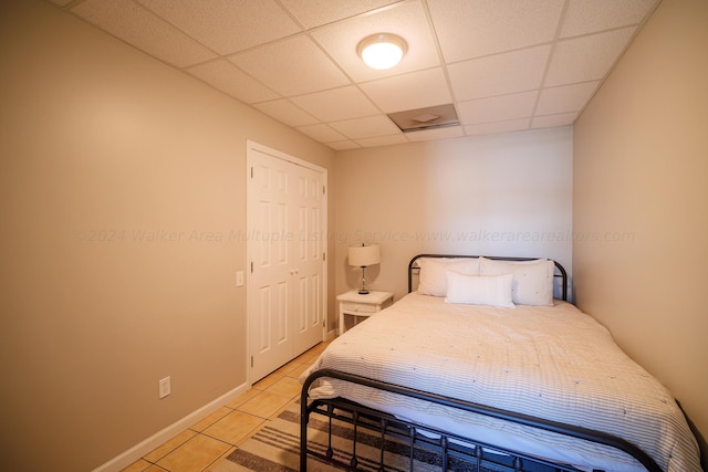 bedroom with tile patterned floors, a drop ceiling, and a closet