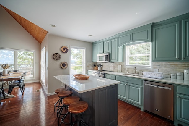 kitchen featuring dark hardwood / wood-style flooring, sink, a kitchen island, and appliances with stainless steel finishes