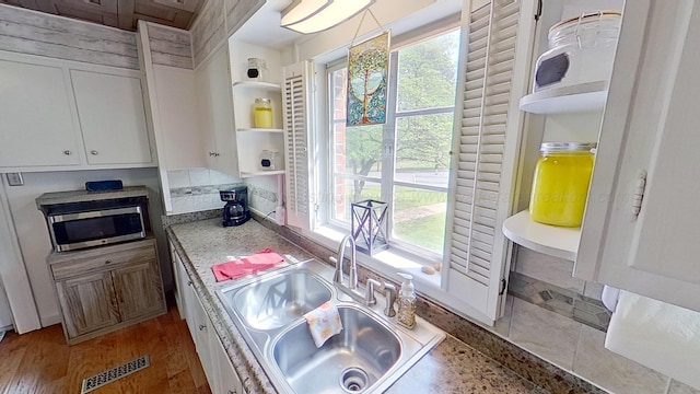 kitchen with white cabinets, plenty of natural light, wood-type flooring, and sink