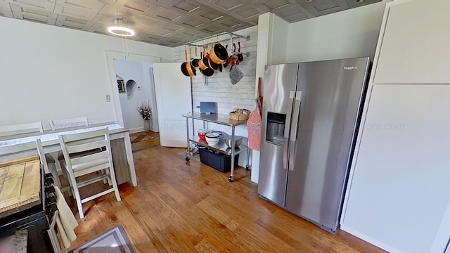 kitchen with white cabinets, stainless steel fridge with ice dispenser, and light hardwood / wood-style floors