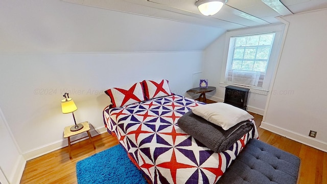 bedroom with wood-type flooring and vaulted ceiling