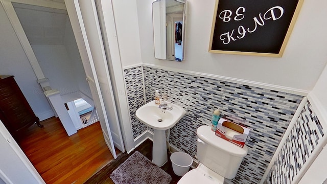 bathroom with toilet, wood-type flooring, and backsplash