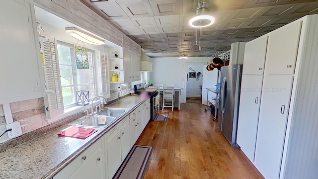 kitchen featuring appliances with stainless steel finishes, light hardwood / wood-style floors, white cabinetry, and sink