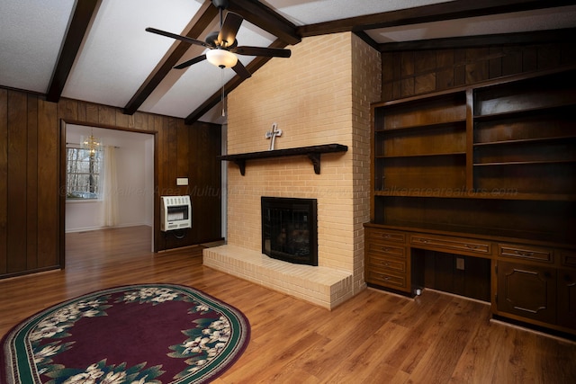 living room featuring light hardwood / wood-style flooring, wooden walls, heating unit, a fireplace, and lofted ceiling with beams