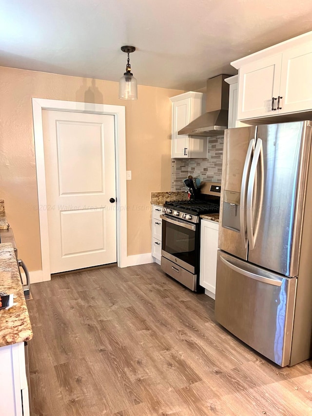 kitchen featuring white cabinetry, wall chimney exhaust hood, light stone countertops, and appliances with stainless steel finishes