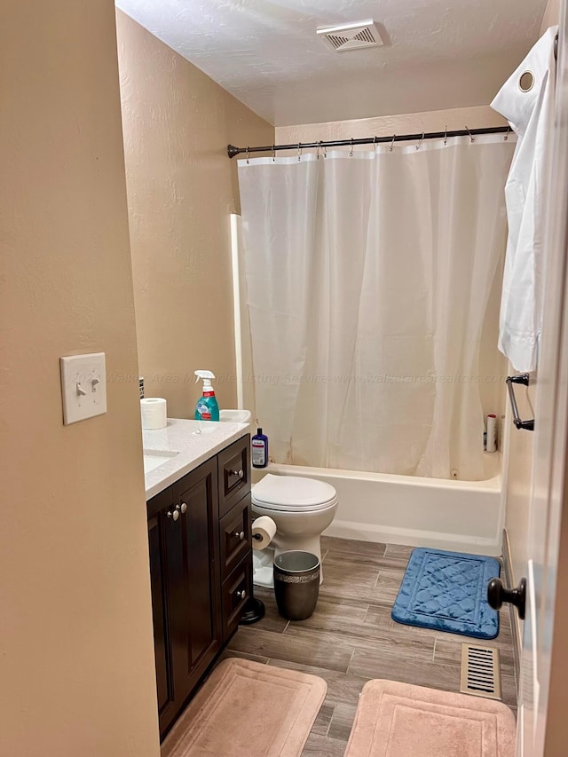 full bathroom featuring vanity, shower / bath combo, hardwood / wood-style flooring, toilet, and a textured ceiling