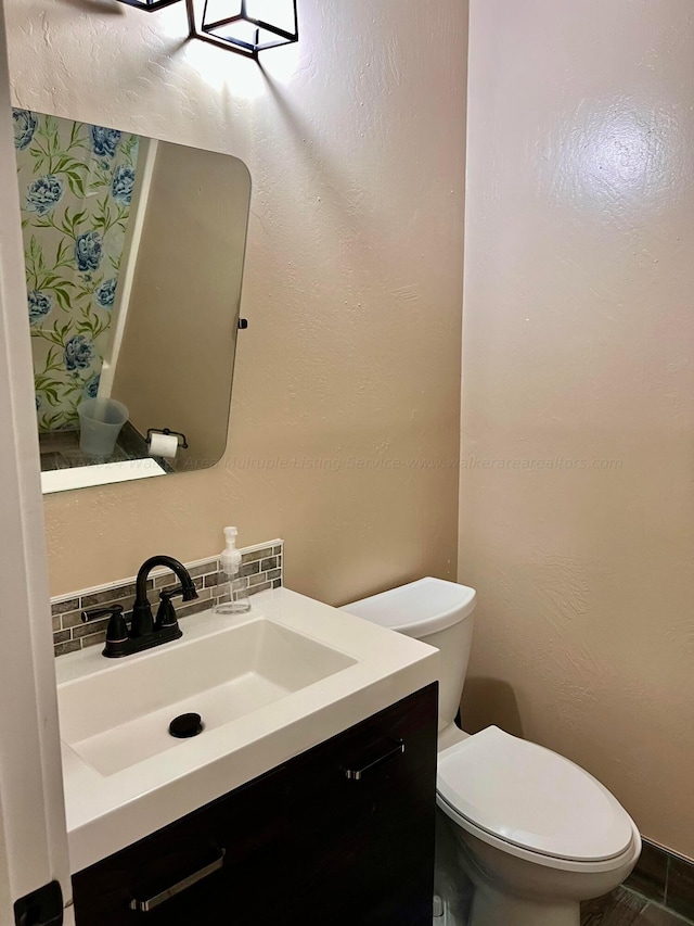 bathroom featuring vanity, tasteful backsplash, and toilet