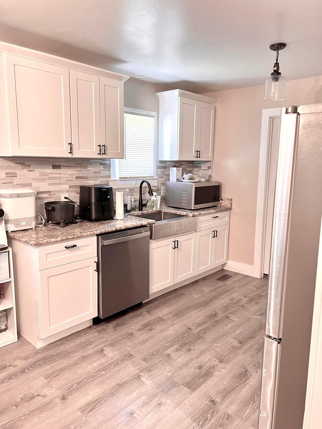 kitchen featuring decorative backsplash, stainless steel appliances, white cabinetry, and light hardwood / wood-style floors