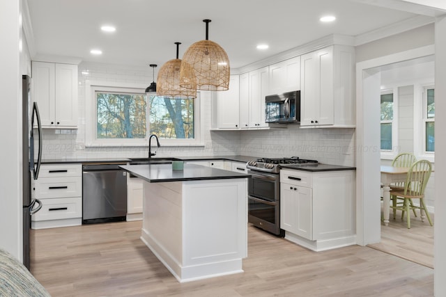 kitchen with stainless steel appliances, dark countertops, light wood-type flooring, and a sink