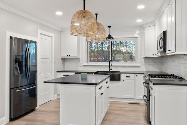 kitchen featuring stainless steel appliances, dark countertops, a sink, and light wood-style floors