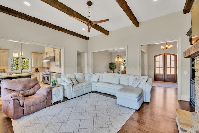 living room featuring arched walkways, light wood-style flooring, recessed lighting, ceiling fan with notable chandelier, and beamed ceiling