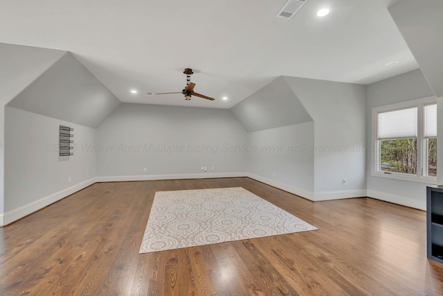 additional living space featuring lofted ceiling, wood finished floors, visible vents, and baseboards