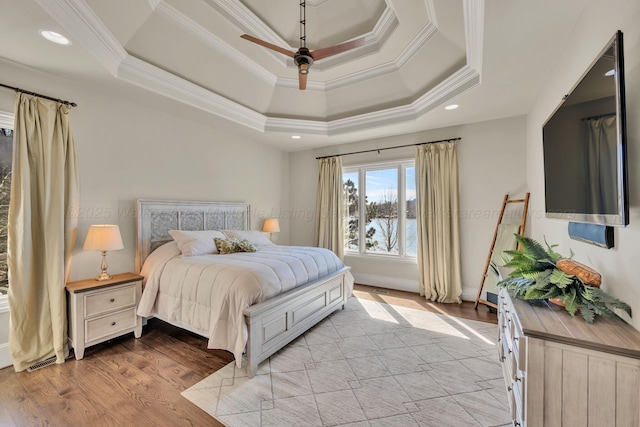 bedroom featuring light wood finished floors, a tray ceiling, ornamental molding, and recessed lighting