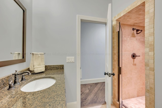 full bathroom with a tile shower and vanity