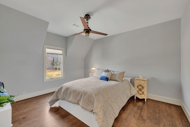 bedroom with baseboards, visible vents, vaulted ceiling, and dark wood-style flooring