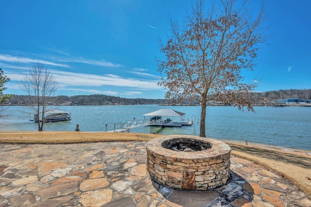 view of patio / terrace with a fire pit, a boat dock, and a water view