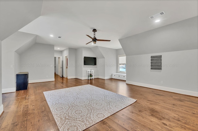 additional living space featuring baseboards, visible vents, vaulted ceiling, and dark wood finished floors