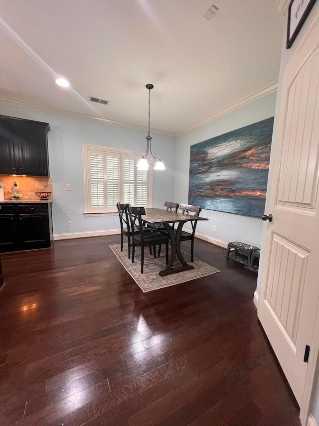 dining room with dark hardwood / wood-style floors, ornamental molding, and an inviting chandelier