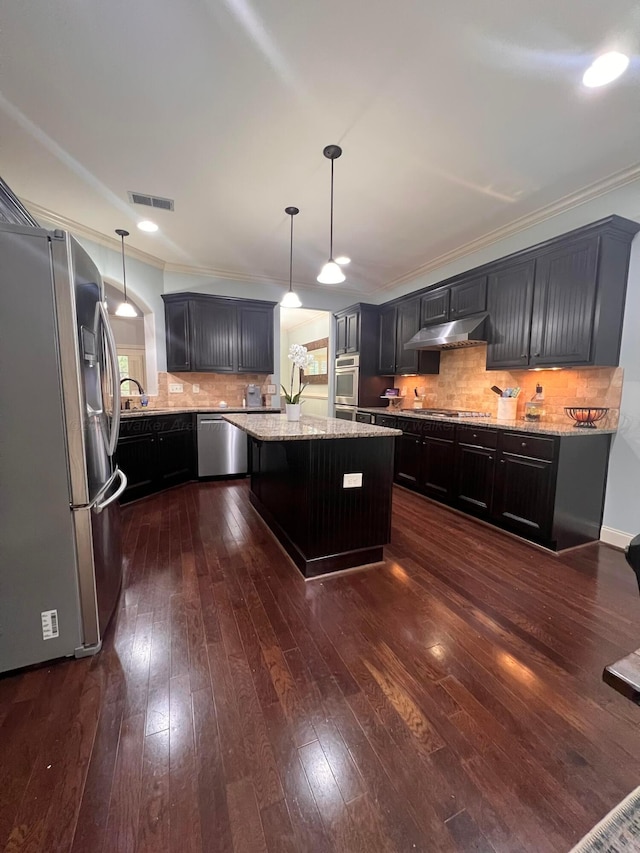 kitchen with stainless steel appliances, light stone counters, hanging light fixtures, and a kitchen island