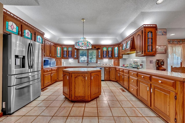 kitchen with pendant lighting, sink, appliances with stainless steel finishes, a center island, and decorative backsplash