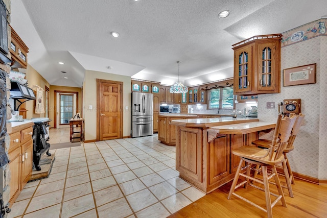 kitchen featuring pendant lighting, a breakfast bar, appliances with stainless steel finishes, a textured ceiling, and a kitchen island