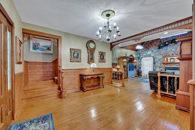 interior space featuring an inviting chandelier, hardwood / wood-style floors, wooden walls, and a textured ceiling