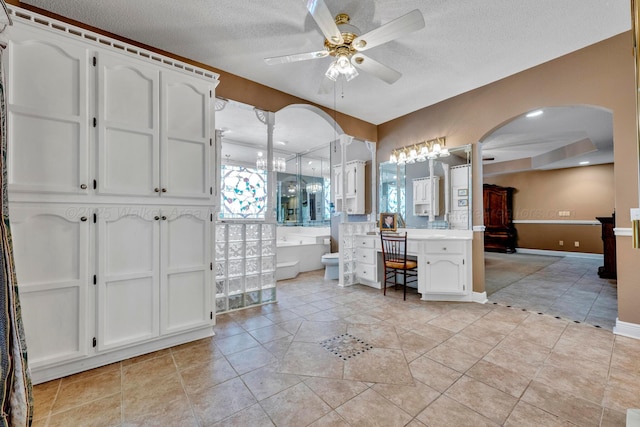 bathroom with ceiling fan, vanity, a textured ceiling, a tub, and toilet