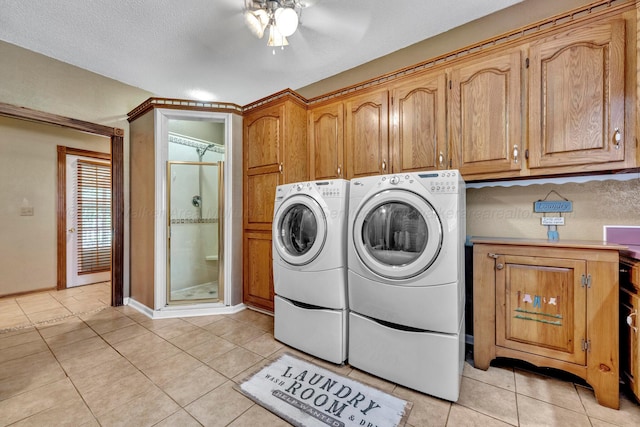 washroom with independent washer and dryer, light tile patterned floors, cabinets, and a textured ceiling