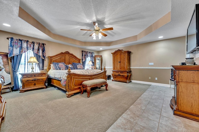 carpeted bedroom featuring ceiling fan, a raised ceiling, and a textured ceiling