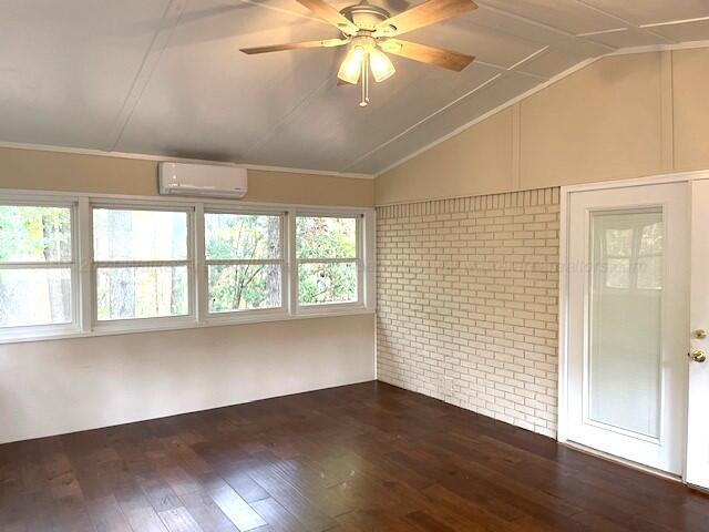 unfurnished sunroom featuring an AC wall unit, ceiling fan, and vaulted ceiling