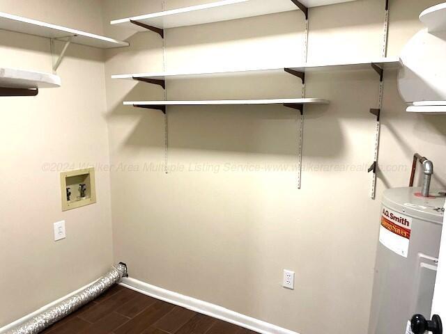 washroom with washer hookup, dark wood-type flooring, and water heater