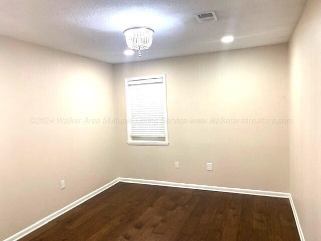 unfurnished room with hardwood / wood-style flooring and a chandelier