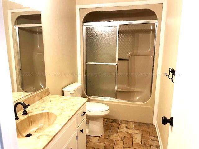 full bathroom with vanity, toilet, and enclosed tub / shower combo