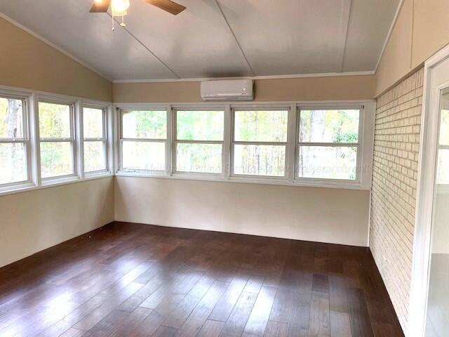 unfurnished sunroom featuring a wall unit AC, ceiling fan, and lofted ceiling