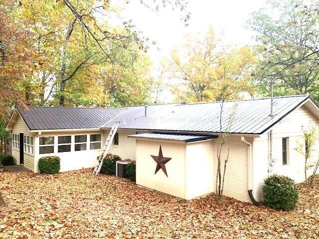 rear view of property featuring central air condition unit and a sunroom