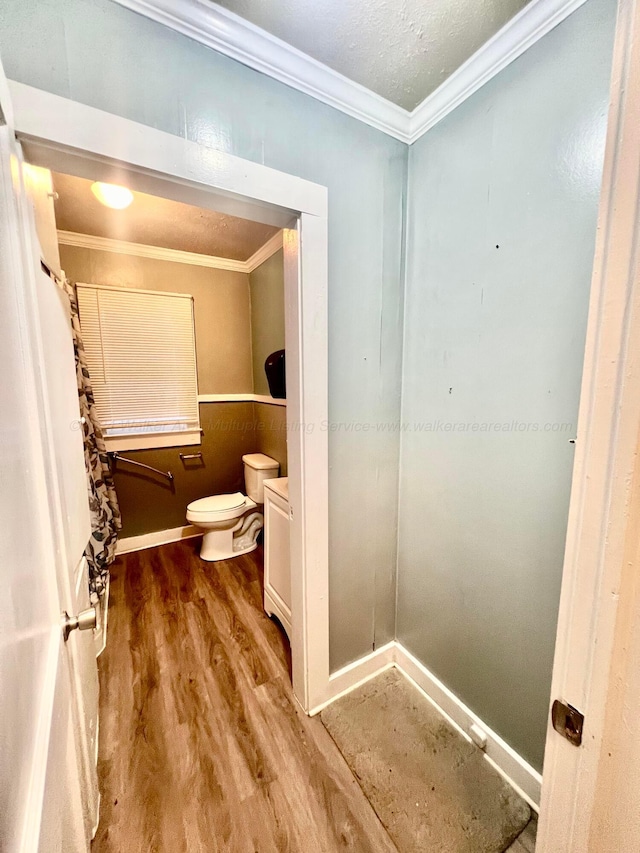 bathroom with wood-type flooring, toilet, and ornamental molding