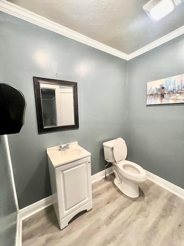 bathroom with hardwood / wood-style floors, vanity, toilet, and ornamental molding