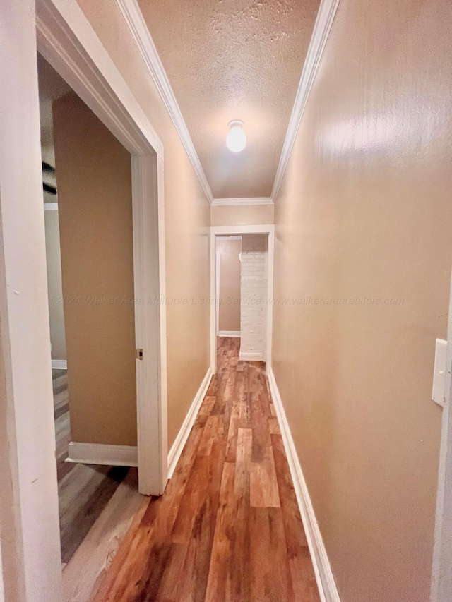 hallway featuring wood-type flooring, a textured ceiling, and ornamental molding