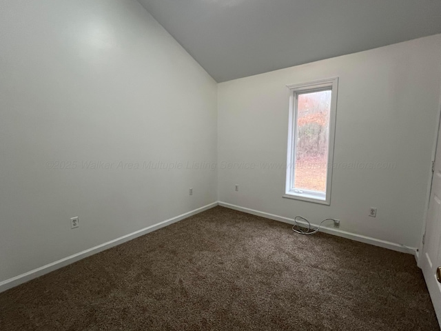 carpeted spare room with vaulted ceiling