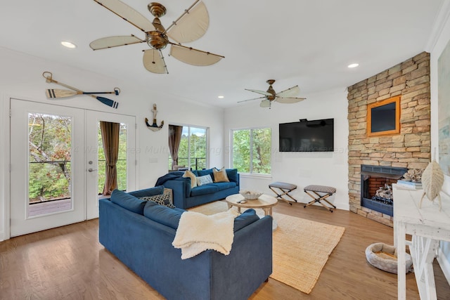 living room featuring hardwood / wood-style floors, a stone fireplace, and a wealth of natural light