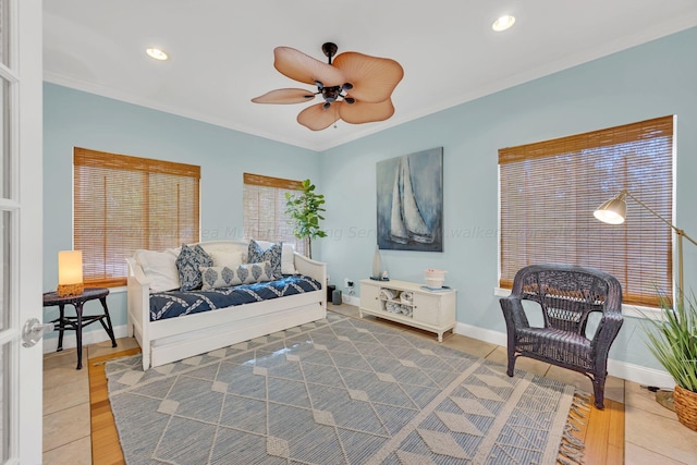 living area featuring ceiling fan, wood-type flooring, and crown molding