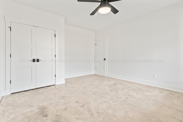 unfurnished bedroom with a closet, baseboards, concrete flooring, and ceiling fan