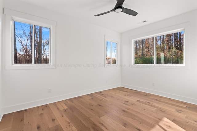 unfurnished room with visible vents, baseboards, and hardwood / wood-style floors