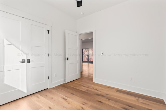 unfurnished bedroom featuring ceiling fan, baseboards, and light wood-style floors