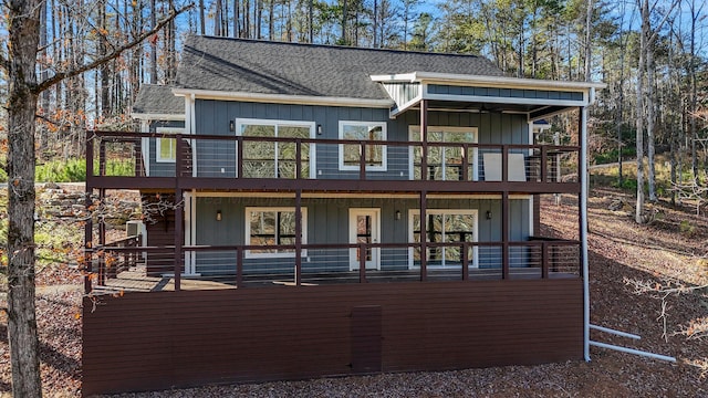 view of front facade featuring a wooden deck, board and batten siding, and a shingled roof