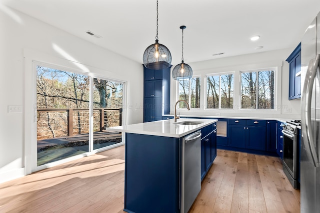 kitchen featuring light wood-type flooring, stainless steel appliances, blue cabinets, and a sink