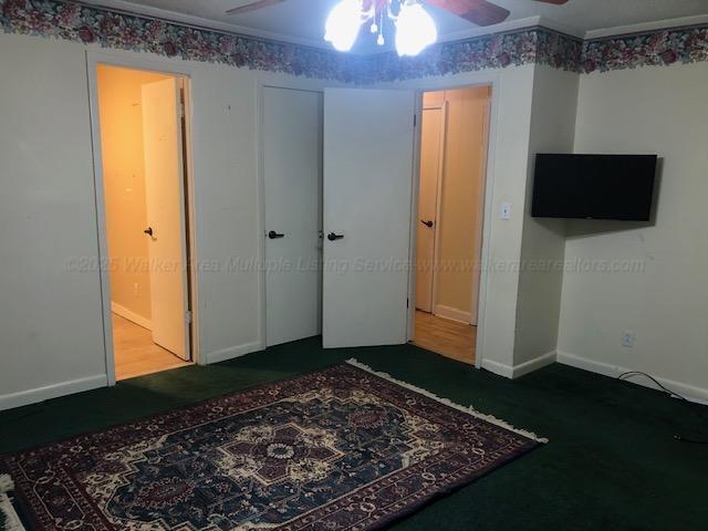 unfurnished bedroom with a closet, baseboards, a ceiling fan, and carpet floors